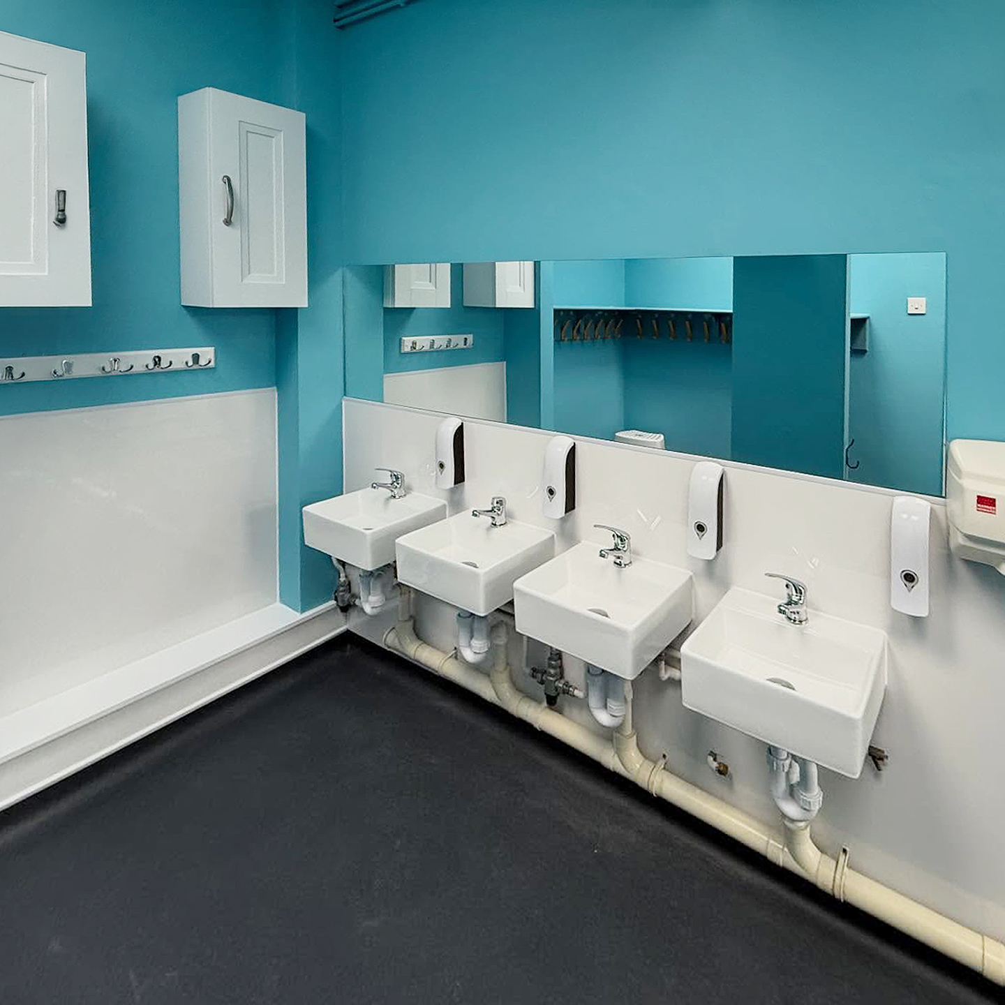Row of wall-hung basins in a blue and white commercial washroom